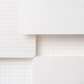 A stack of Large Blackwing Slate Notebooks showcasing paper types - dot-grid, blank, ruled, and graph